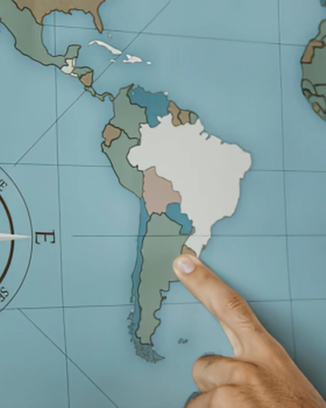a finger pointing at South America on an atlas